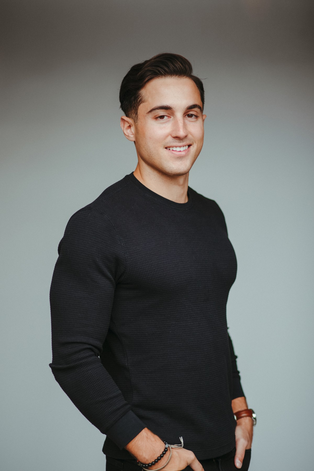 Jacob Tyler Ramos smiling in a black sweater against a gray studio background